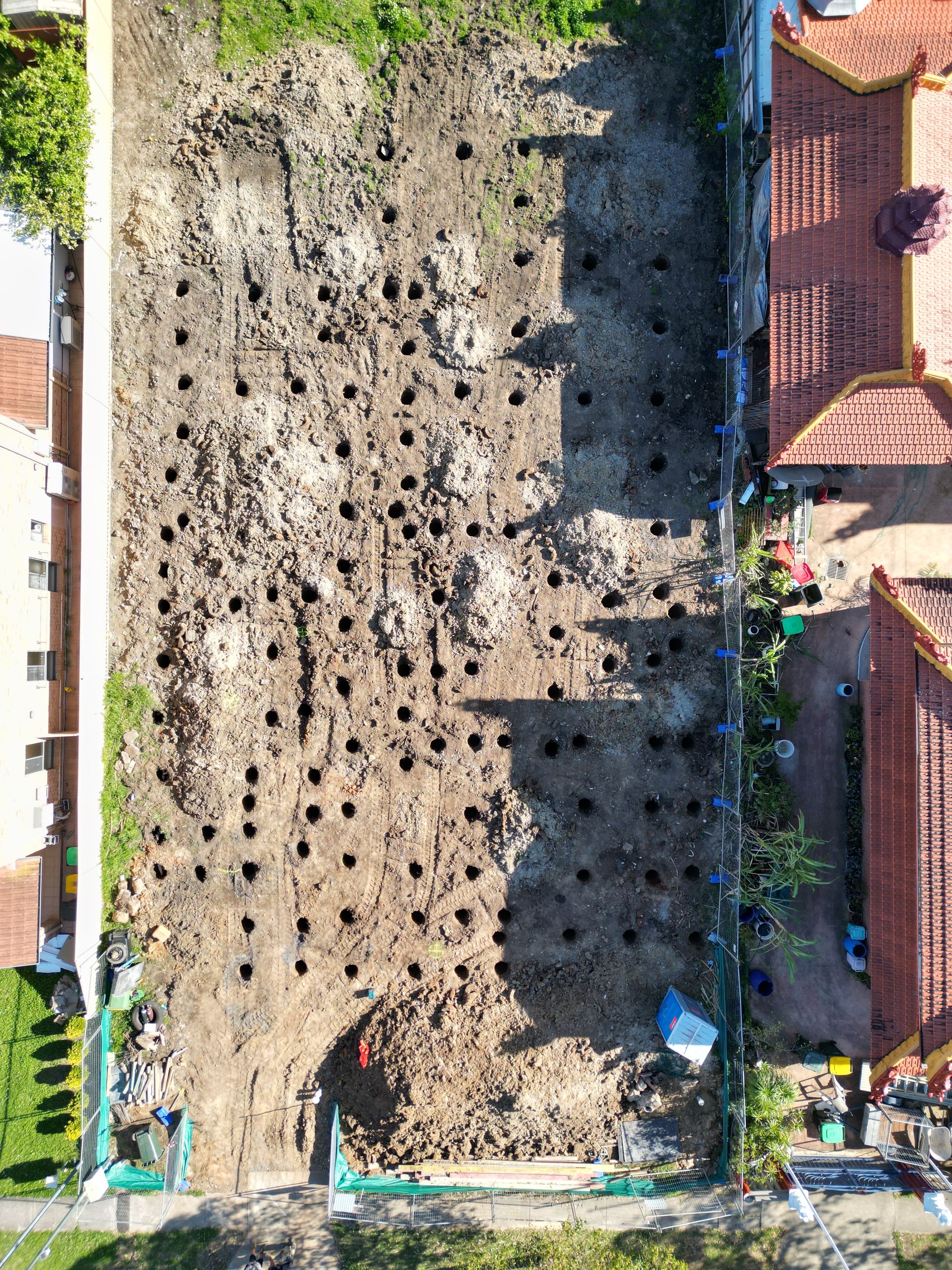 Directly overhead view of the cleared site showing a dense grid of bored pier holes across the whole footprint.